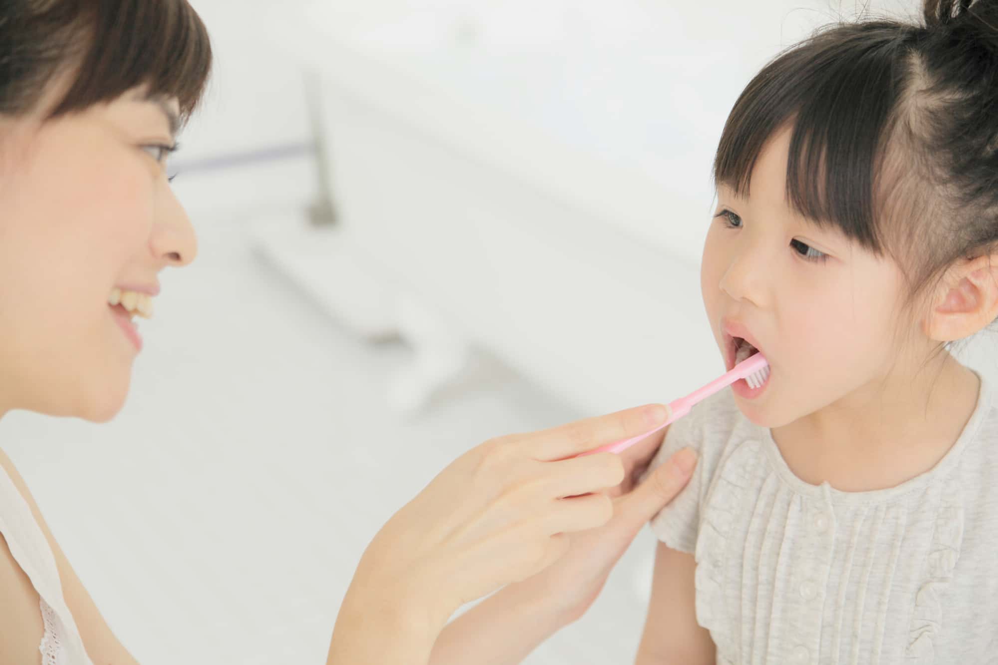 乳歯の虫歯予防に仕上げの歯磨きをする親子