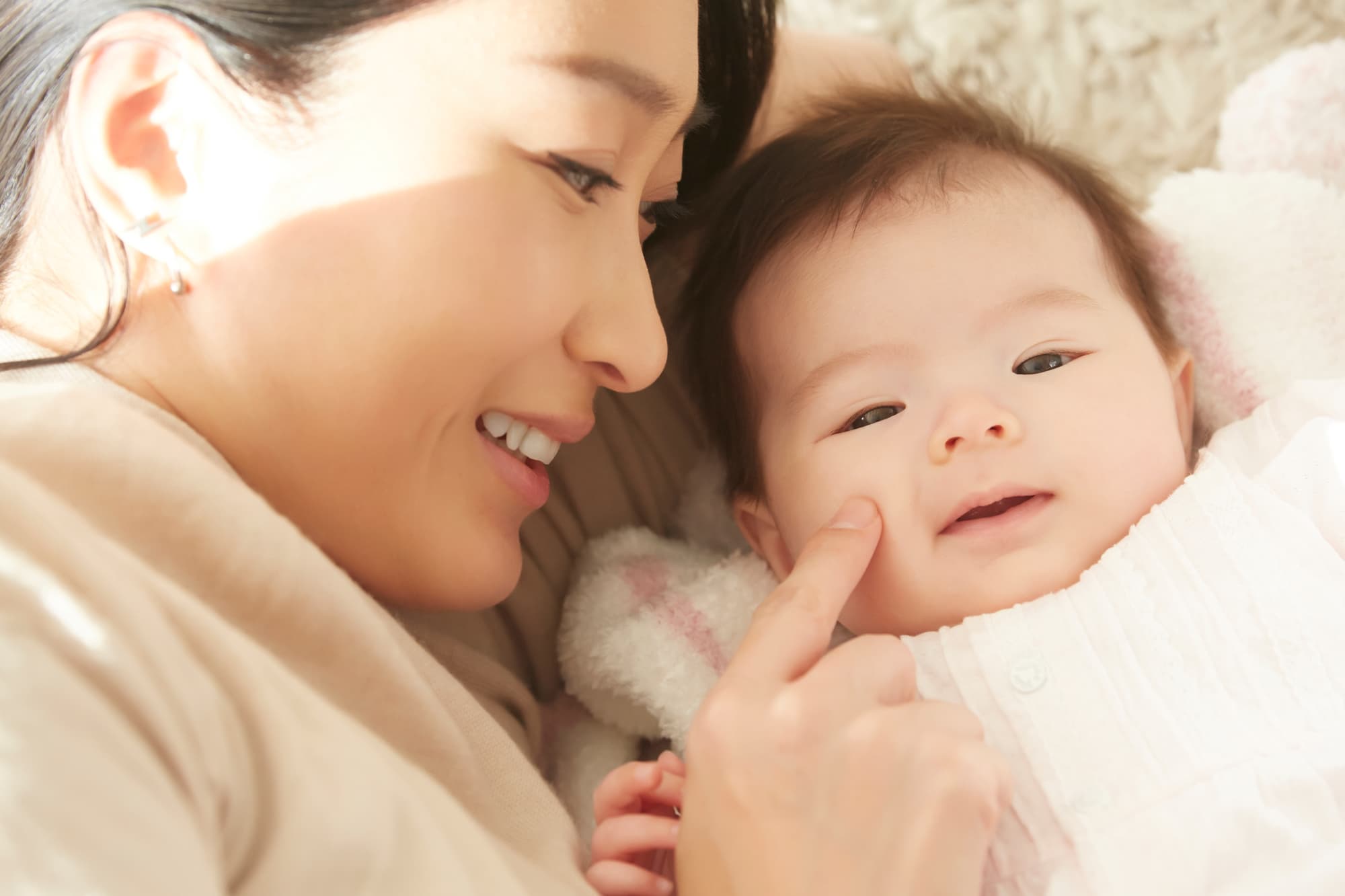 赤ちゃんのほっぺを愛おしそうに指で触れる母親
