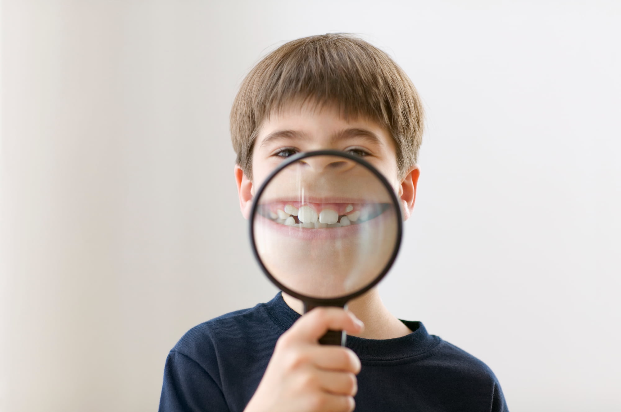 出っ歯に虫眼鏡をあてて拡大して見せる子ども