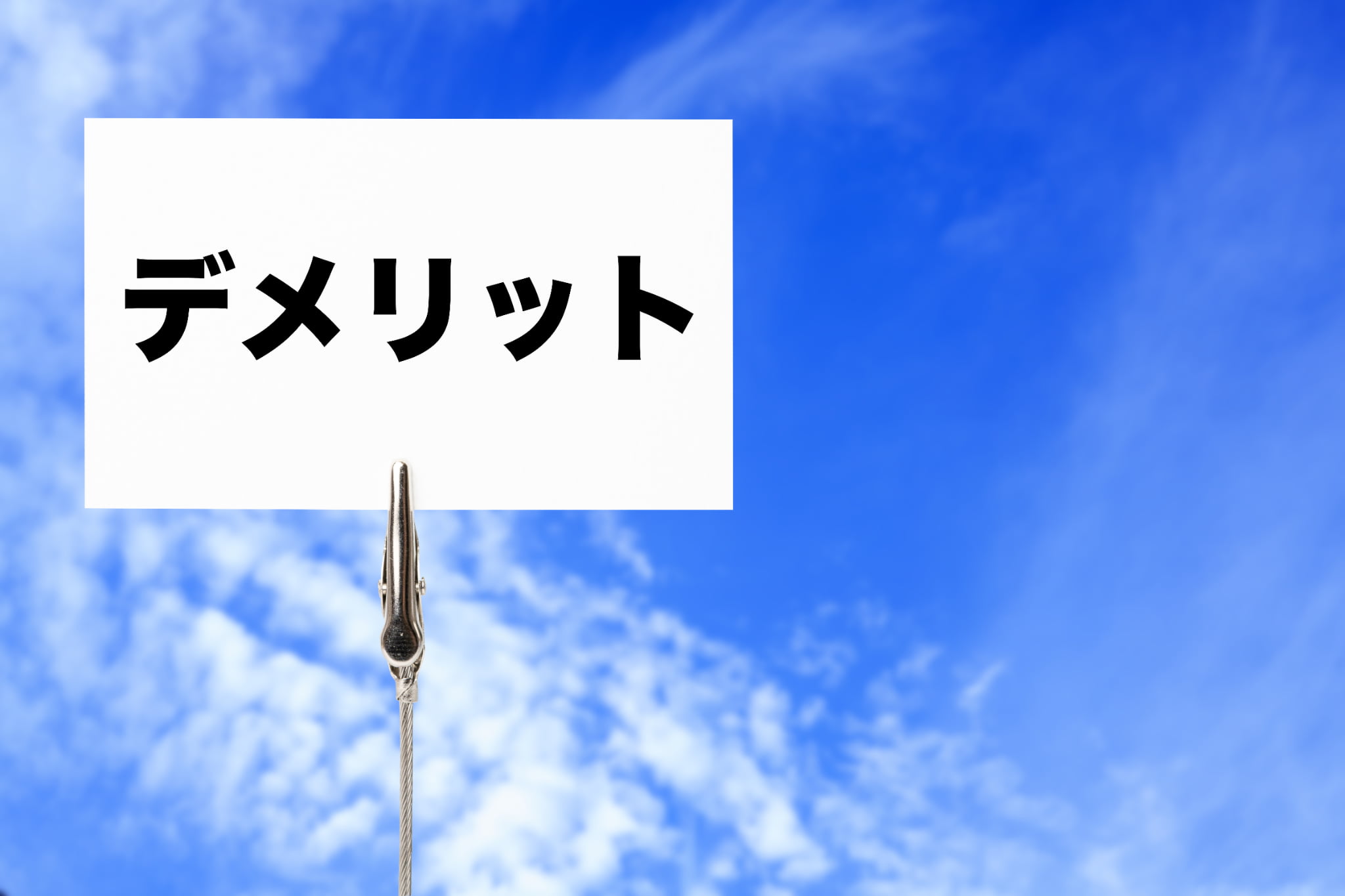 青空を背景にデメリットと書かれたカード