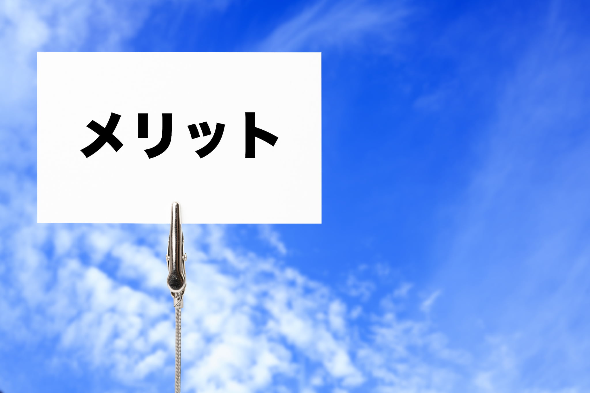 青空を背景にメリットと書かれたカード