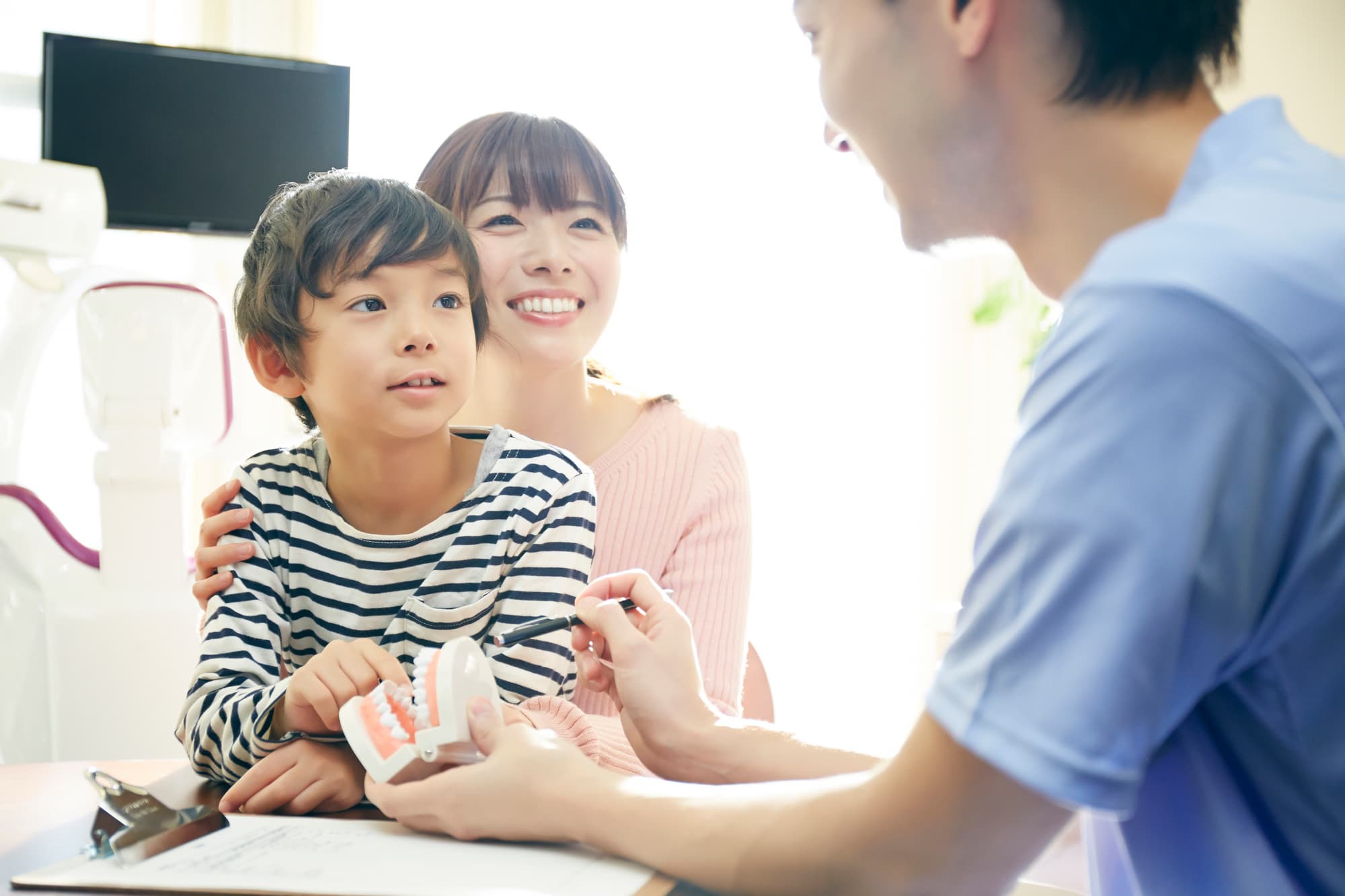 マイオブレースの治療について歯科医からカウンセリングを受ける親子