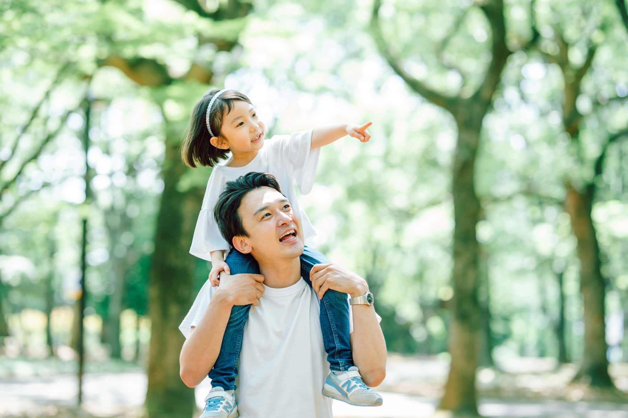 林を散歩する娘を肩車した父親