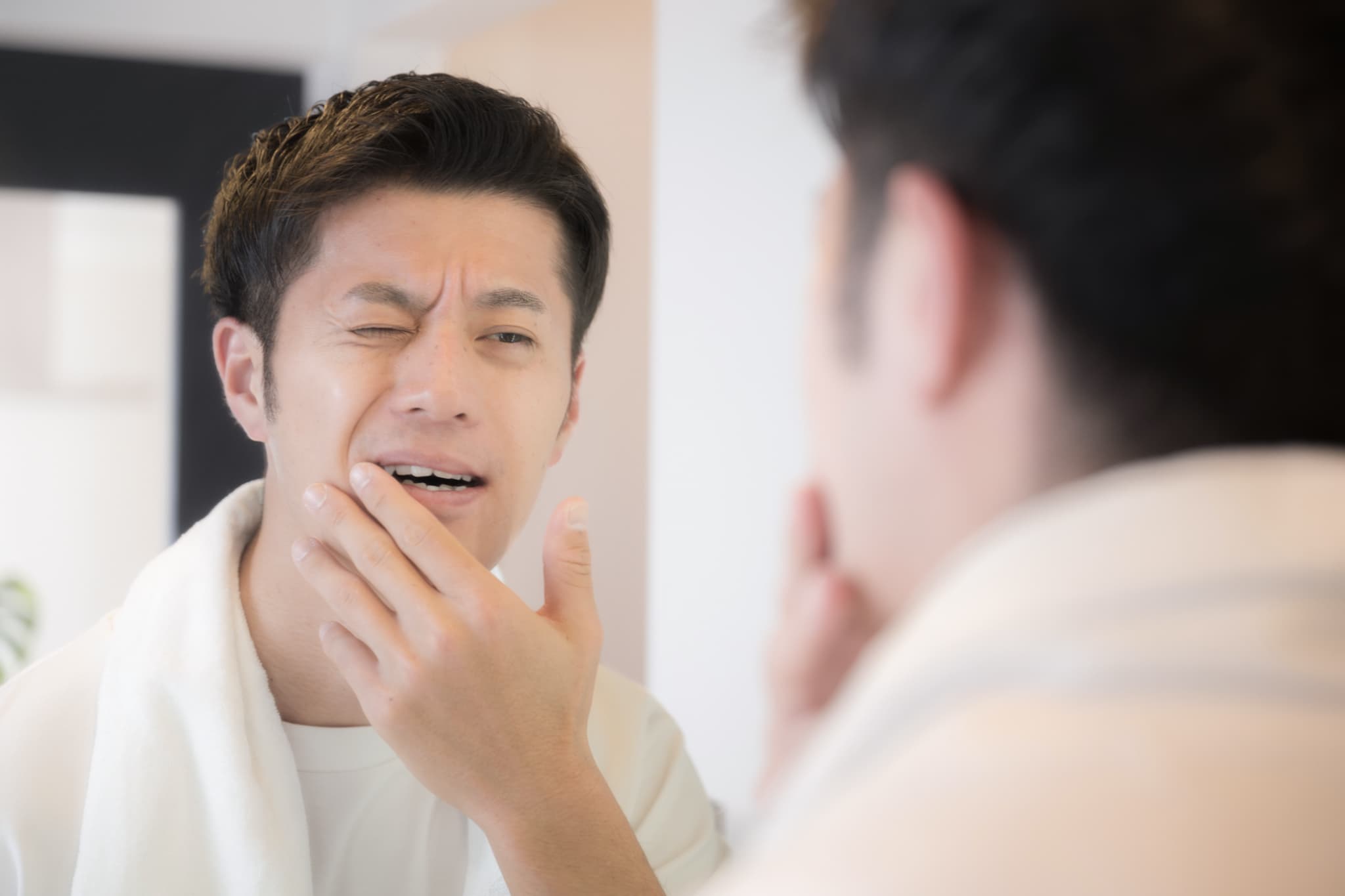 違和感のある歯を鏡で確認している歯を失いやすい年ごろの40代男性